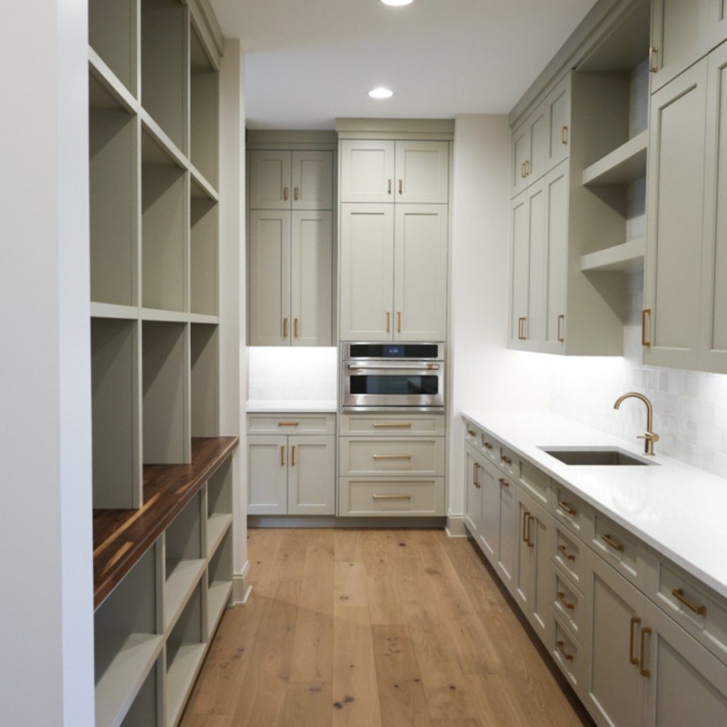 Sage green butler’s pantry with butcher block countertops and full kitchen view in custom Elkhorn home.